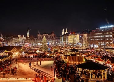 Night view of the Zurich Christmas market featuring an outdoor ice skating rink and festive stalls.