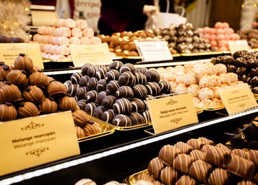 Assorted gourmet marzipan pralines and chocolate truffles displayed at a European Christmas market.
