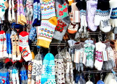 Display of colorful handmade wool socks and knitted mittens with Nordic patterns at a winter market.