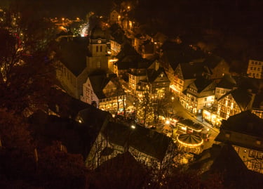 Aerial night view of a German Christmas market with half-timbered houses and festive lights.