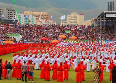 Performers in traditional Mongolian attire carry flags during a Naadam festival ceremony in a crowded stadium.
