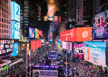 Crowds celebrate New Year's Eve in Times Square New York with confetti, fireworks, and bright digital billboards.