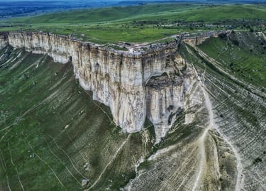 Aerial view of the massive White Rock limestone cliff formation in a green valley landscape.