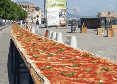A record-breaking long pizza margherita on a table along the Lungomare Caracciolo in Naples, Italy.