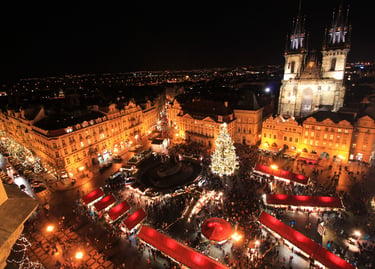 Aerial night view of Prague Old Town Square Christmas market with a glowing tree and Tyn Church.