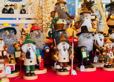 Handcrafted German incense smoker dolls and wooden nutcrackers at a traditional Christmas market.