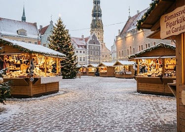 Snowy Christmas market in Riga Old Town featuring wooden stalls and a decorated tree.