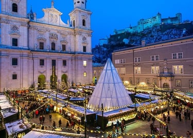 Salzburg Christmas market at night with festive lights, the Cathedral, and Hohensalzburg Fortress.
