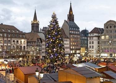 A giant lit Christmas tree stands in the center of the Strasbourg Christmas Market at dusk.