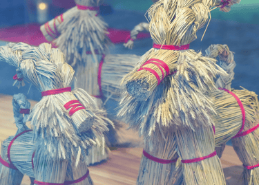 Traditional Swedish Yule Goat figurines made of straw and red ribbons on display in a window.