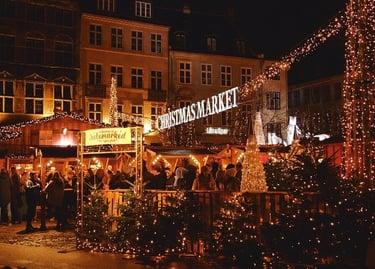 Crowds visit a festive outdoor Christmas market at night decorated with glowing fairy lights and trees.