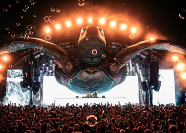 DJs perform on a massive sea turtle stage with bubbles and bright lights at a crowded music festival.