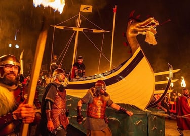 Vikings in traditional armor pulling a wooden longship during the Up Helly Aa fire festival.