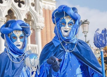 Two performers wearing ornate blue costumes and masks at the Carnival of Venice in Italy.