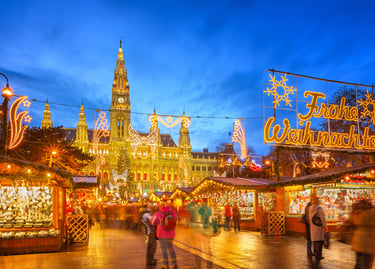 Vienna Christmas Market at Rathausplatz with festive lights, stalls, and illuminated City Hall at night.