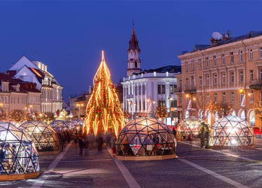 Christmas market at night in Vilnius, Lithuania, featuring a glowing tree and glass igloo domes.