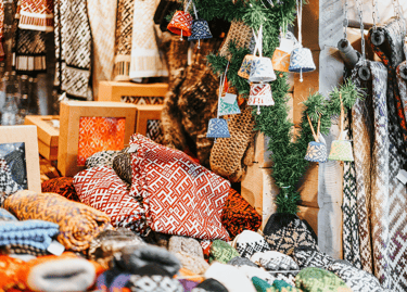Traditional knitted wool mittens and sweaters with Nordic patterns at a festive outdoor Christmas market stall.