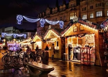 Festive wooden stalls and glowing lights at the Sheffield Christmas Market at night.