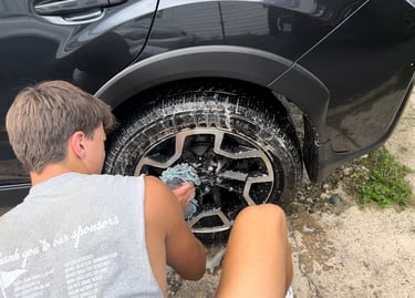 Golden mobile detailing team giving an SUV an exterior wash on its rims and tires
