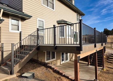 Finished elevated deck with black metal railing and integrated stairs by Elk Valley Contractors.