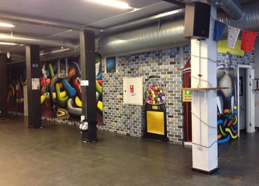 Urban interior featuring colorful street art graffiti on brick walls and a gumball machine mural.