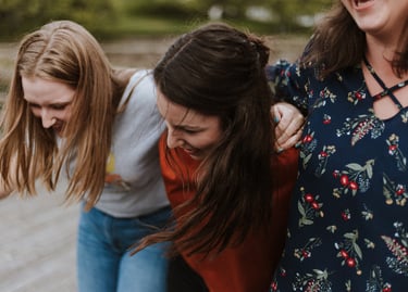 Three ladies side by side, with their arms around each others' shoulders