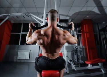 A muscular bodybuilder performs a lat pulldown exercise to strengthen his back muscles in a gym.