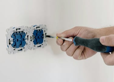 un électricien munit d'un tournevis réparant une prise électrique