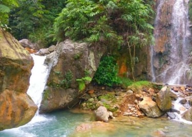 Air terjun Curug Ciburial yang sejuk mengalir di antara pepohonan rimbun ke kolam alami yang tenang, menampilkan suasana asri
