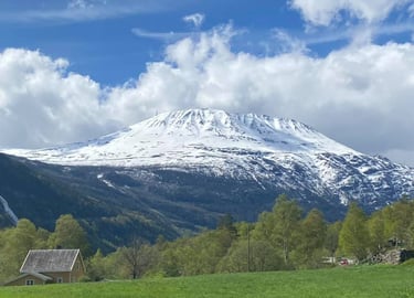 snow covered mount gausta with treeline and house and in the foreground