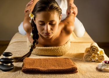 a long haired lady relaxes, eyes closed while the masseuse stretches and puls her 2 arms to her back