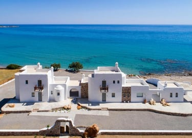 Luxury white villas with traditional Greek architecture overlooking the blue Mediterranean Sea.