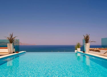 Luxury infinity pool overlooking the blue Mediterranean Sea at a summer vacation resort.