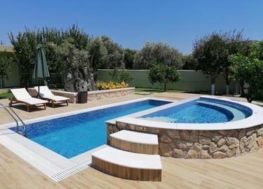 Luxury backyard swimming pool and integrated hot tub with wood deck and lounge chairs.