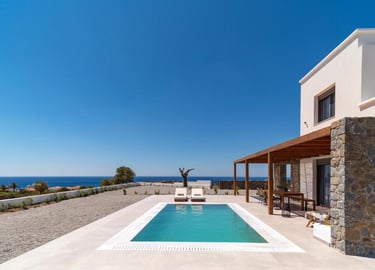 Luxury villa with a private swimming pool and sea view terrace under a clear blue sky.