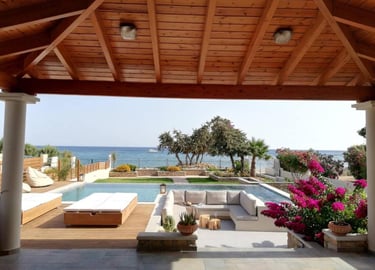 Luxury beachfront villa patio with a swimming pool, sunken lounge, and ocean view under a wood pergola.