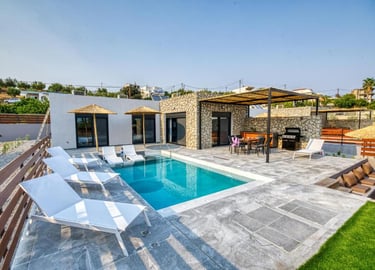 Luxury villa with private swimming pool, sun loungers, and stone patio dining area.