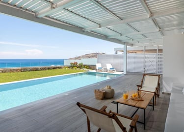 Luxury villa terrace with private infinity pool overlooking the blue ocean under a white pergola.