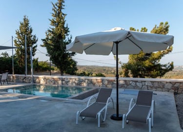 Luxury patio with lounge chairs, white umbrella, and a private pool overlooking a scenic valley.