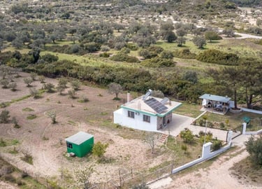 Aerial view of a sustainable countryside villa with solar panels and an outdoor kitchen in a rural olive grove.