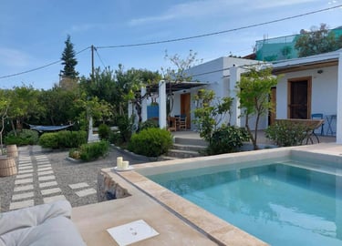 Luxury white villa with a small swimming pool and stone path in a Mediterranean garden.