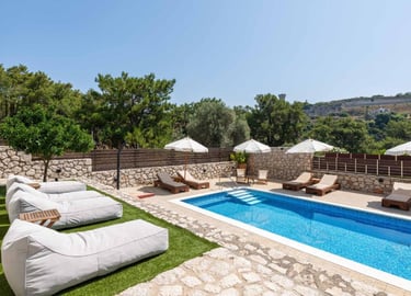 Luxury private villa with swimming pool, sun loungers, and bean bags on a sunny terrace.