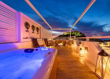 Luxury rooftop terrace with hot tub and lounge seating overlooking a scenic sunset mountain.