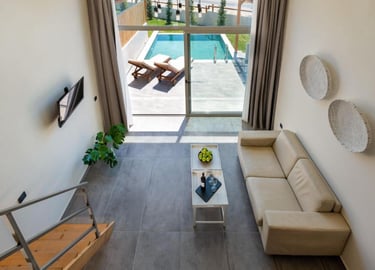 Modern luxury villa interior with a living room overlooking a private outdoor swimming pool.