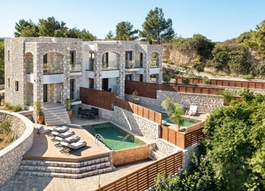 Luxury stone villas with private infinity pools and sun loungers overlooking a lush green landscape.