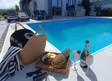 Luxury vacation scene with a swimming pool, champagne, and fresh fruit at a modern villa.