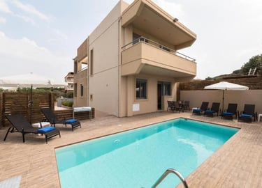 Modern luxury villa with a private swimming pool, sun loungers, and outdoor patio furniture.