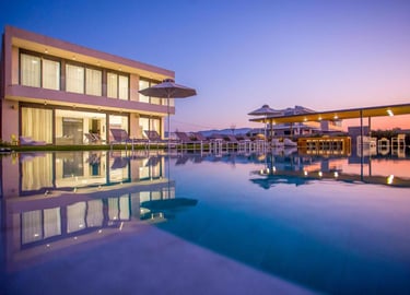 Luxury modern villa with an outdoor infinity pool and lounge chairs at sunset.