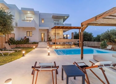 Luxury modern villa with a private swimming pool, outdoor lounge area, and patio at twilight.