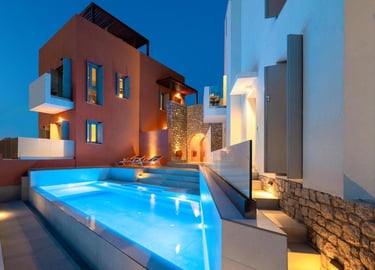 Luxury villa with illuminated infinity pool and modern architecture at twilight.